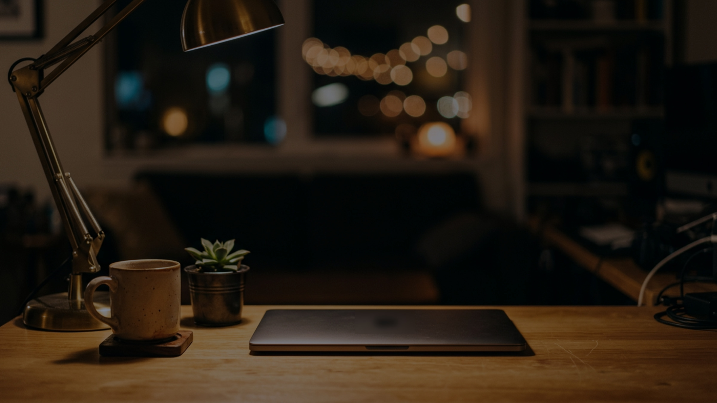 A warm-lit desk at night in navy tones